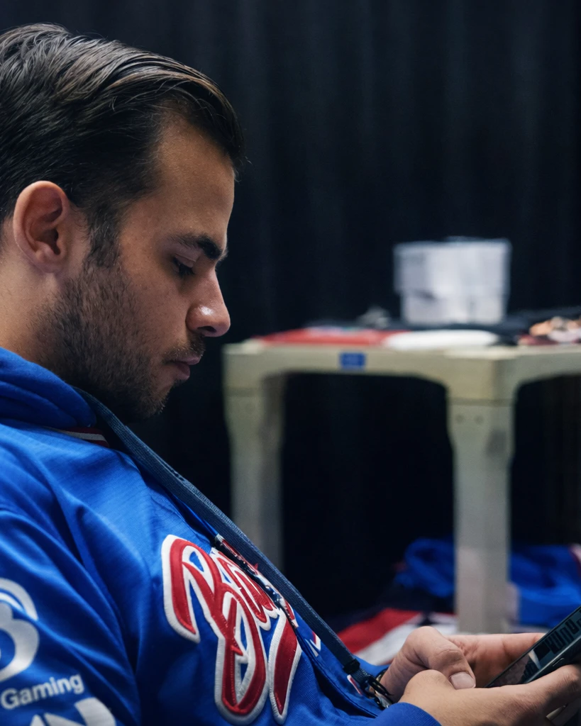 Gabriel Garrido looking at a phone while wearing a blue esports jersey